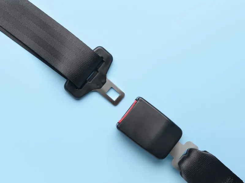 A seatbelt tongue plate and buckle receiver with their webbing sections, laid out flat and separated on a plain light background.